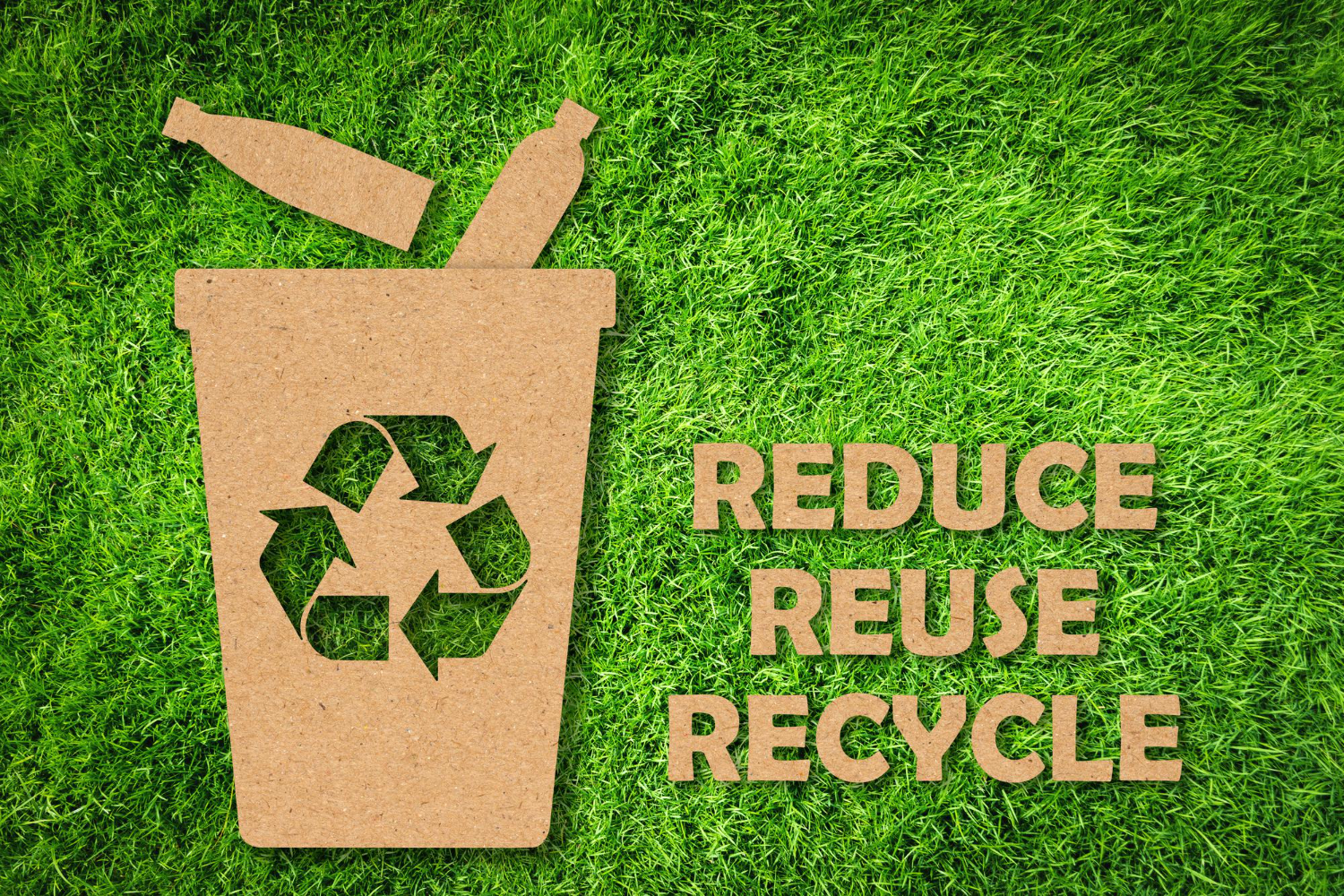 Kraft-paper-cut-reuse-reduce-recycle-symbol-text-green-grass-background-environmental-conservation-concept